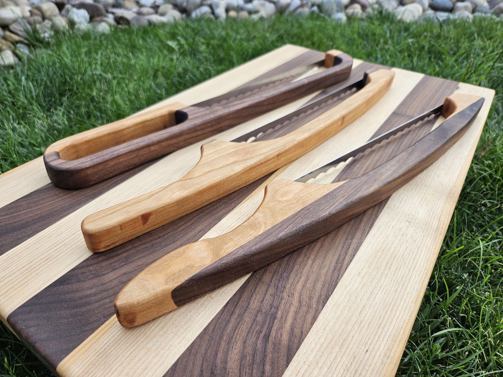 Handmade bread bow knives in walnut and cherry on a striped board